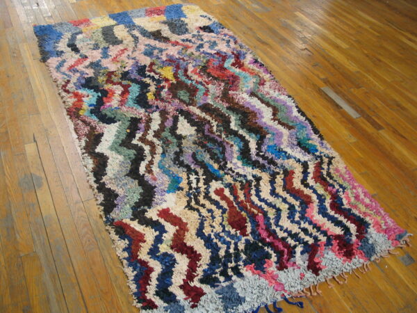 Textural, multicolored rug featuring jagged, wavy stripes sits on a honey-toned wood floor.