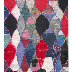 Shaggy multicolor rug with an irregular patchwork design of overlapping red, black, and bright diamonds.