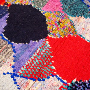 Close-up of a highly textured rug featuring multicolored abstract patches in red, navy, turquoise, and yellow.
