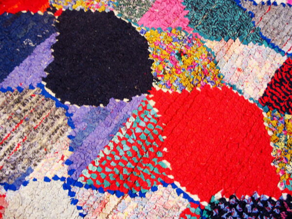 Close-up of a highly textured rug featuring multicolored abstract patches in red, navy, turquoise, and yellow.