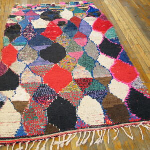 Vibrant high-pile rug with abstract red, black, pink, and blue patchwork diamonds on a wood floor.