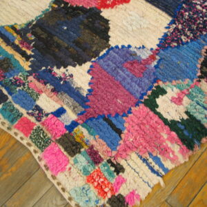 Brightly colored, high-pile patchwork rug with pink, blue, purple, and white segments on a wood floor.