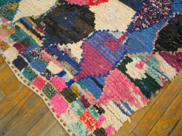 Brightly colored, high-pile patchwork rug with pink, blue, purple, and white segments on a wood floor.
