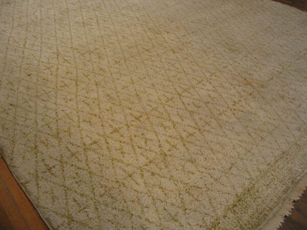 Beige shag rug with subtle criss-cross gold patterns lying on dark wood flooring.