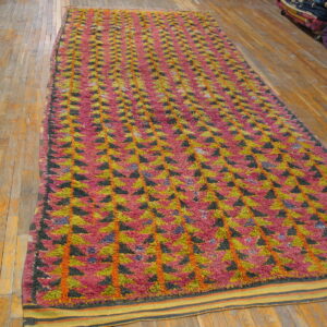 High-pile rug with pink, lime green, and black triangles arranged in vertical rows on hardwood floor.
