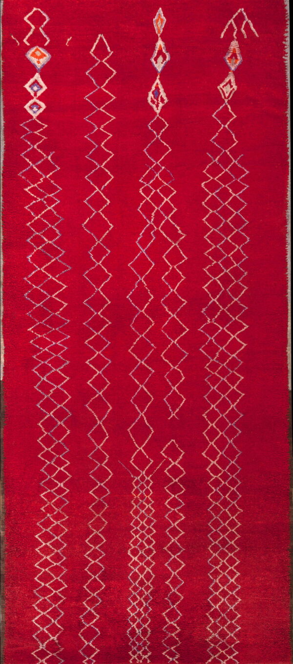 Red, high-pile runner rug featuring four vertical rows of continuous white and multicolored diamond patterns.