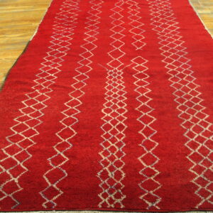 High-pile red rug featuring vertical columns of white diamond patterns on a light wood plank floor.