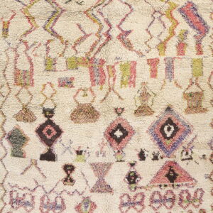 High-pile cream rug with asymmetrical geometric patterns in pink, purple, olive, and dark brown colors.