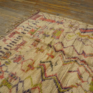 Shaggy cream rug with colorful geometric patterns in pink, purple, and bright green on wood floor.