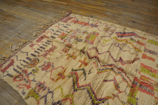 Shaggy cream rug with colorful geometric patterns in pink, purple, and bright green on wood floor.