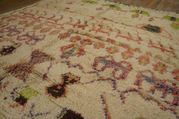 High-pile shag rug in cream with abstract pink, purple, green, and brown patterns over wood floors.
