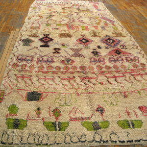 Textured cream rug with abstract pink, green, and dark designs on warm wood flooring.