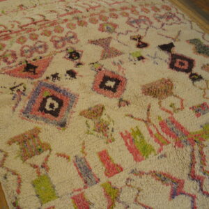 Shaggy off-white rug with vibrant pink, green, and purple abstract geometric patterns on wood flooring.