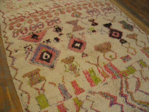 Shaggy off-white rug with vibrant pink, green, and purple abstract geometric patterns on wood flooring.