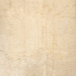 Close-up texture of a solid cream-colored rug featuring a deep, plush, shaggy pile.