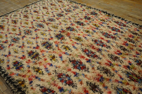 Shaggy cream rug featuring multicolored abstract splashes of red, blue, yellow, and black on wood floor.