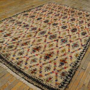 High-pile cream rug with abstract multicolor diamonds and a dark border rests on natural plank wood floors.
