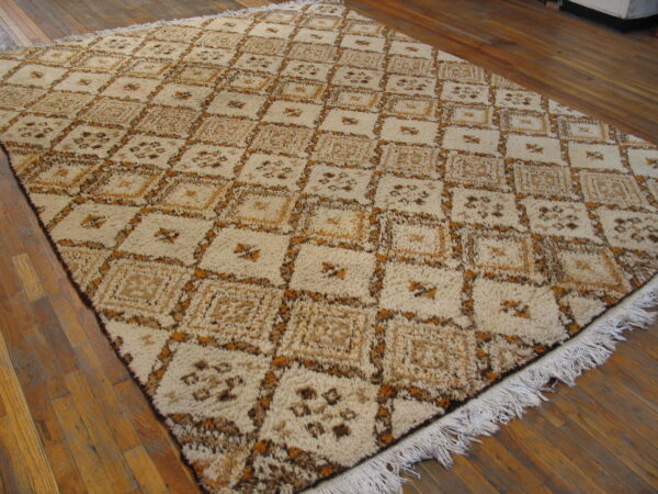 A cream, brown, and tan high-pile rug with a geometric grid pattern rests on wood plank flooring.