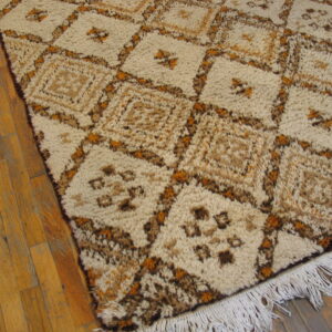 Shaggy cream rug with brown and golden geometric diamonds lies on a honey wood floor.