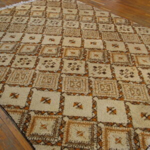 Shaggy rug with beige and brown geometric squares bordered by rust sits on a polished wood floor.