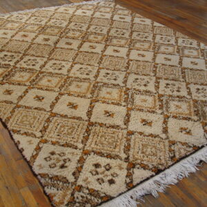 Shaggy beige, brown, and gold rug with a repeating diamond pattern resting on wide plank hardwood flooring.