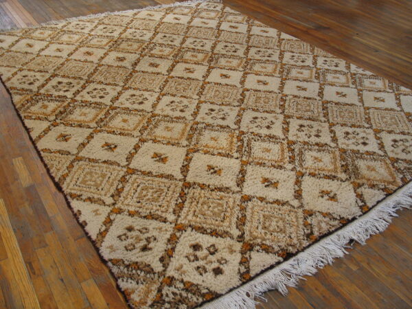 Shaggy beige, brown, and gold rug with a repeating diamond pattern resting on wide plank hardwood flooring.