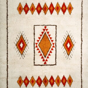 High pile rug in off-white featuring geometric diamonds and crosses in red, orange, and dark brown.