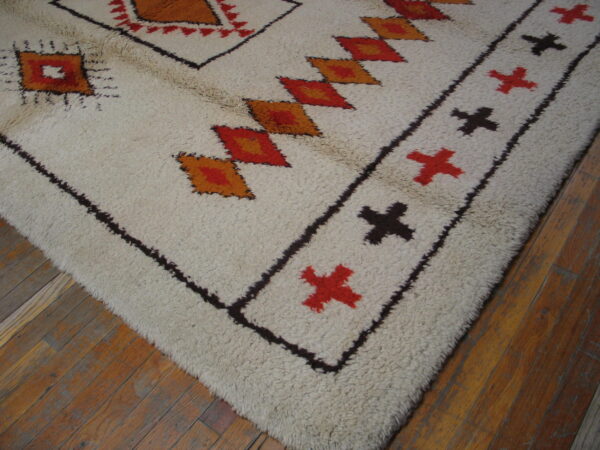 High-pile rug with geometric patterns in cream, brown, red, and orange on distressed wood floors.