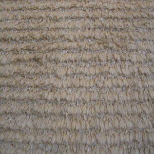Close-up showing the ribbed texture of a high-pile rug in light beige and grey tones.