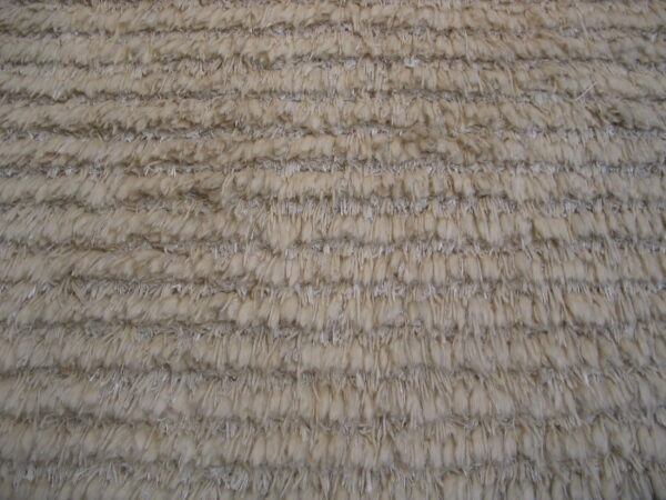 Close-up showing the ribbed texture of a high-pile rug in light beige and grey tones.