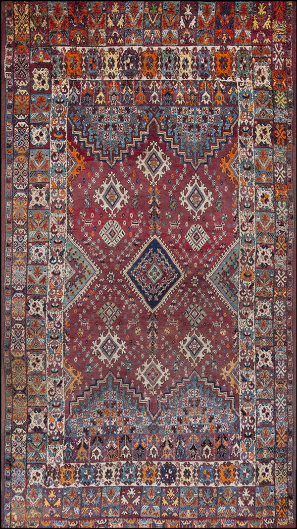 Traditional tribal rug with a maroon field, central diamonds, and wide borders featuring diverse geometric patterns.