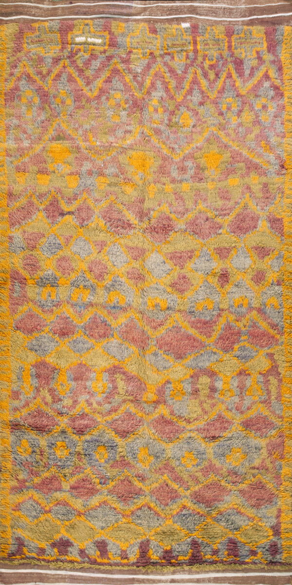 High-pile rug featuring a shaggy geometric diamond pattern in mustard yellow, dusty rose, and gray.