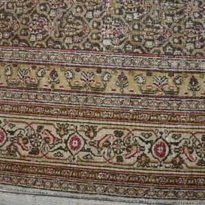 Low-pile rug detail showing borders and field with stylized motifs in tan, dark brown, and burgundy.