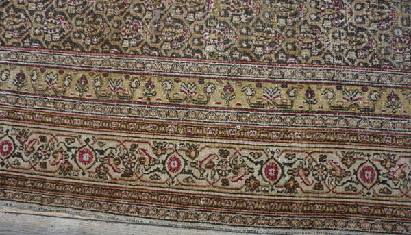 Low-pile rug detail showing borders and field with stylized motifs in tan, dark brown, and burgundy.