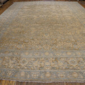 Oversized beige and pale blue distressed traditional area rug laid on rich wooden flooring.