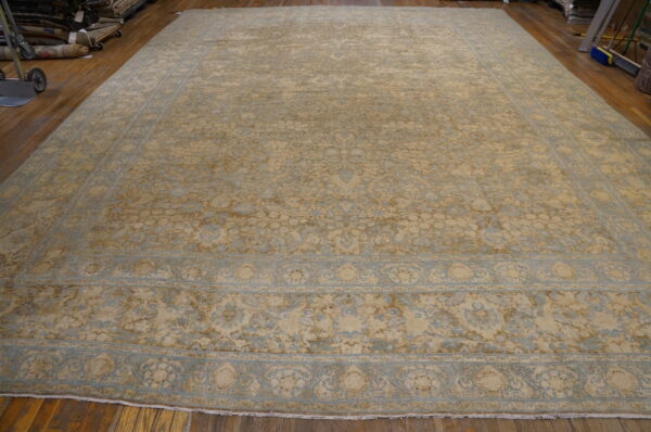 Oversized beige and pale blue distressed traditional area rug laid on rich wooden flooring.