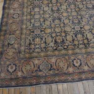 Distressed blue and peach floral patterned rug shown on rustic wide plank wooden flooring.