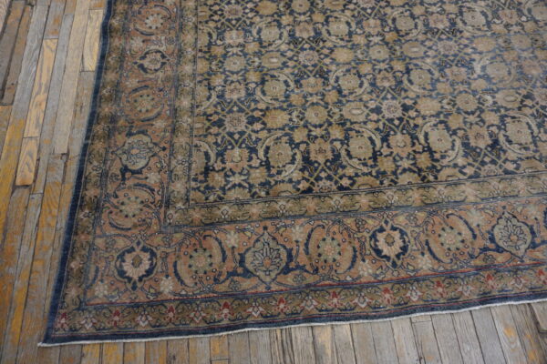 Distressed blue and peach floral patterned rug shown on rustic wide plank wooden flooring.