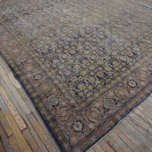 Faded blue, tan, and rose medallion rug with low pile rests on distressed, wide wooden planks.