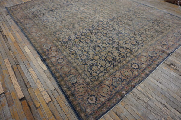 Faded blue, tan, and rose medallion rug with low pile rests on distressed, wide wooden planks.