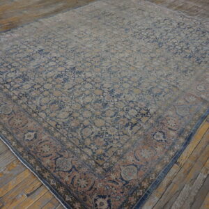 Distressed, patterned rug featuring faded blue and dusty rose floral motifs on plank wood flooring.