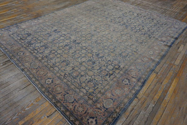 Distressed, patterned rug featuring faded blue and dusty rose floral motifs on plank wood flooring.