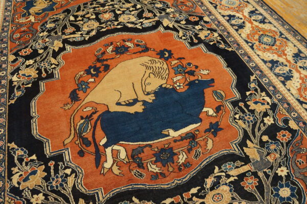 Detailed rust and navy rug featuring a central medallion depicting a lion attacking a blue bull.