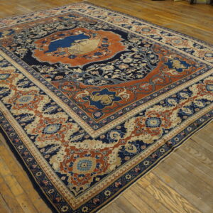Detailed navy blue and burnt orange traditional rug with animal motifs on worn wooden floors.