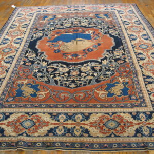 Ornate low-pile rug in blue, rust, and cream with a detailed central medallion rests on glossy wood floors.