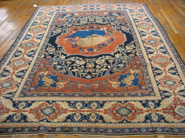 Ornate low-pile rug in blue, rust, and cream with a detailed central medallion rests on glossy wood floors.