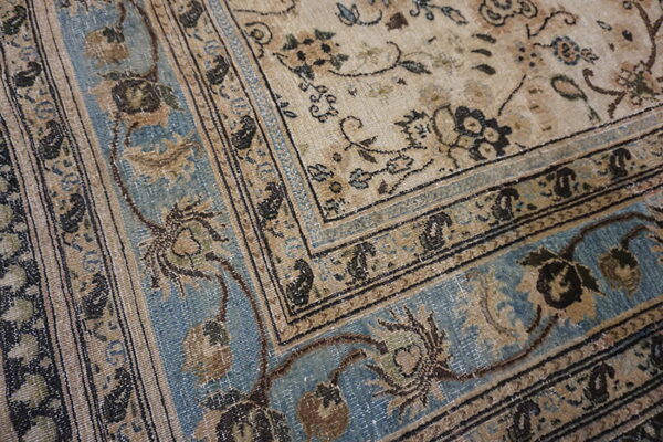Low-pile rug detail with faded beige, distressed blue, and dark brown traditional floral patterns and borders.