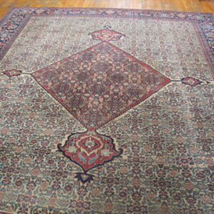 Large traditional beige and red rug with a central diamond medallion and floral design on wood floor.