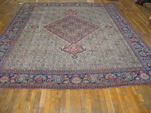 Low-pile rug with a cream field, dense floral design, central red medallion, and wide blue border.