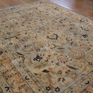 Low-pile rug with a complex botanical pattern in faded blue-green, tan, and brown on hardwood.